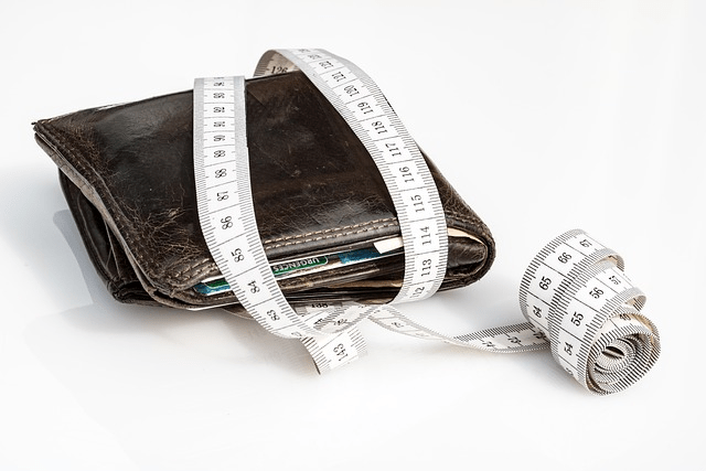 A person looking at VA IRRRL costs and fees, wallet showing a tape measure wrapped around it, constraints on wallet due to mortgage payment and mortgage insurance